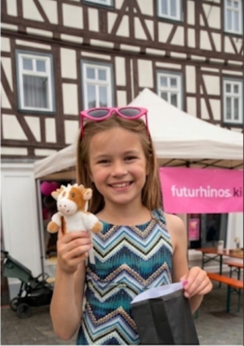 Mädchen freut sich über ihr Kuscheltier als Gewinn (Kind KI-anonymisiert)