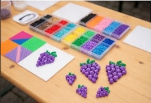 Bügelperlen in vielen Farben und Vorlagen für Pixel-Art-Trauben auf dem Tisch