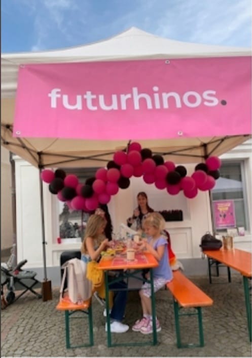 Der Futurhinos-Stand mit pinkem Banner und Ballongirlande auf dem Oberen Marktplatz